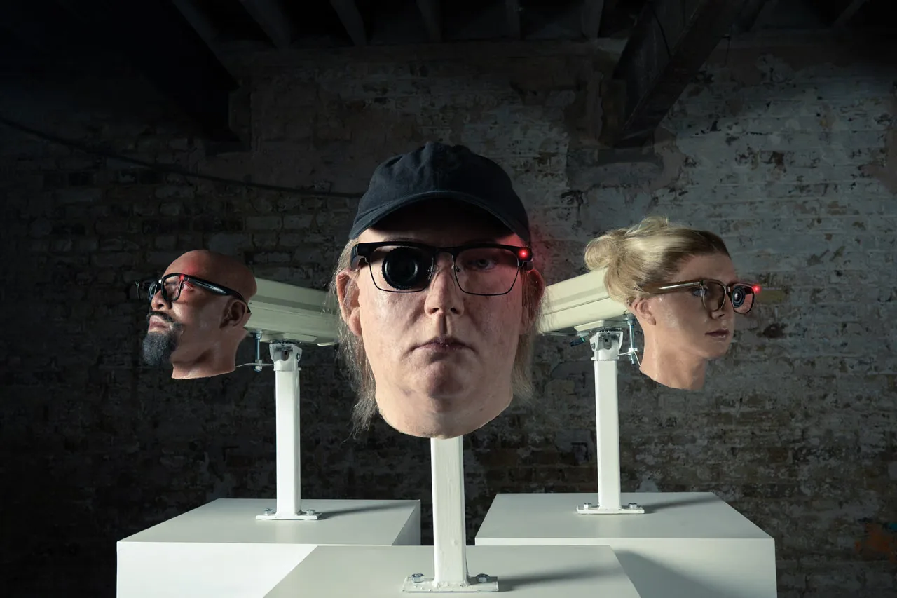 Even Realities public installation of three sculpted heads wearing camera glasses on white plinths in Soho, London by The Robin Collective