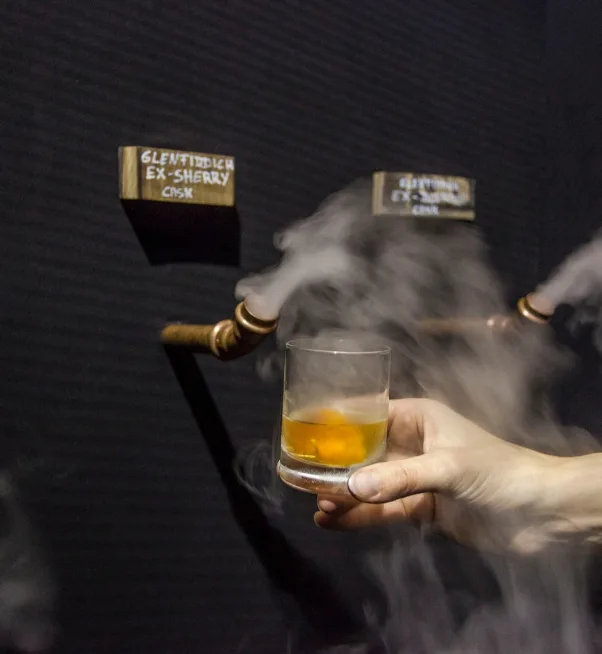Glass of Glenfiddich Ex-Sherry Cask whisky served from a smoking copper pipe installation