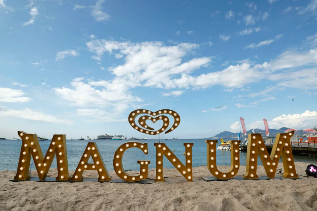 Giant illuminated MAGNUM marquee letters on the beach at Cannes Film Festival with the Mediterranean sea behind