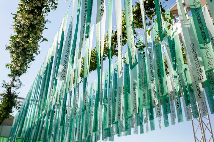 Hanging green ribbon installation printed with dream phrases at Pinterest Beach Cannes Lions